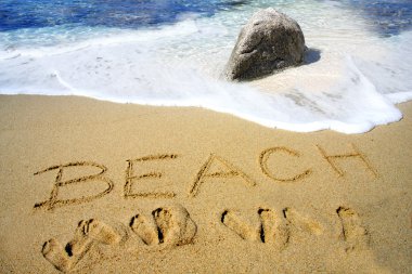 Beach handwritten in sand on a beac clipart