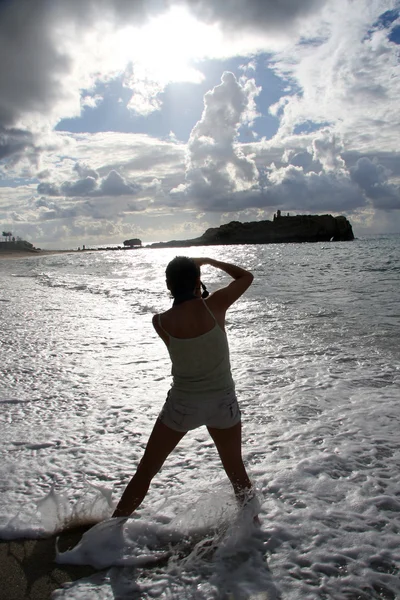 Mooie jonge vrouw permanent op strand, kijkt naar de zee — Stockfoto