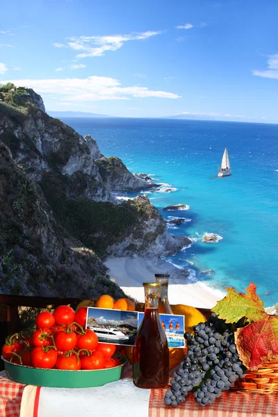 Mesa com vinho e frutas contra iate sozinho no mar azul — Fotografia de Stock