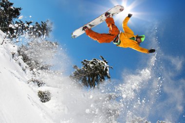 Snowboarder jumping against blue sky clipart