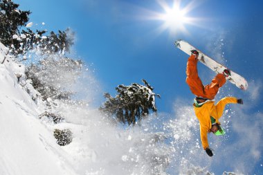 Mavi gökyüzüne atlayan snowboardcu