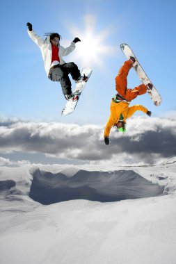 Snowboarders jumping against blue sky clipart