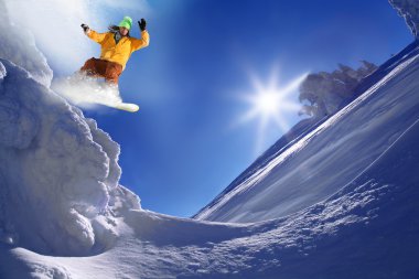 Snowboarder jumping against blue sky clipart