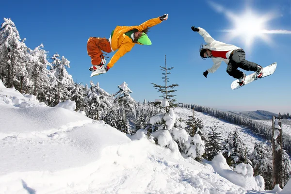 Snowboarders saltando contra o céu azul — Fotografia de Stock
