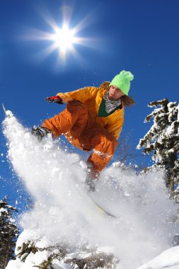 Snowboarder jumping against blue sky clipart