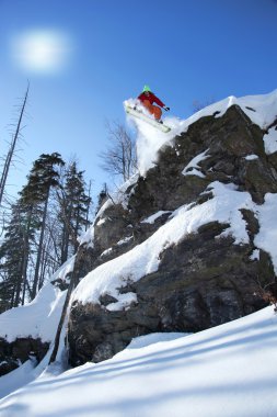 Mavi gökyüzüne atlayan snowboardcu
