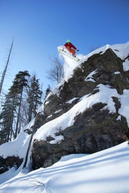 Snowboarder jumping against blue sky clipart