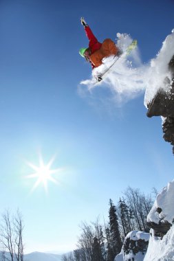 Snowboarder jumping against blue sky clipart