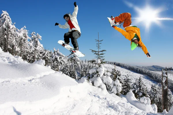 Snowboarders saltando contra el cielo azul — Foto de Stock