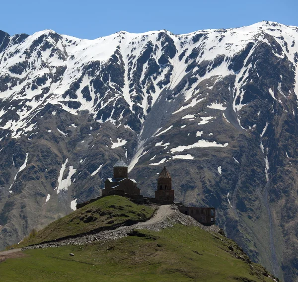 Gergeti Szentháromság-templom és a Kaukázus-hegység. stepantsminda. Grúzia. — Stock Fotó