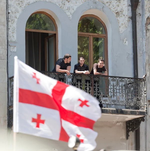 De jeunes hommes regardent le défilé militaire depuis le balcon. Tbilissi, Géorgie . — Photo
