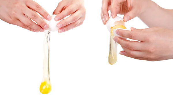 Руки розтріскують сире яйце ізольовано на білому тлі — стокове фото