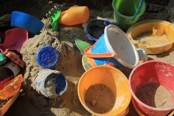 Brinquedos coloridos alegres em uma caixa de areia — Fotografia de Stock