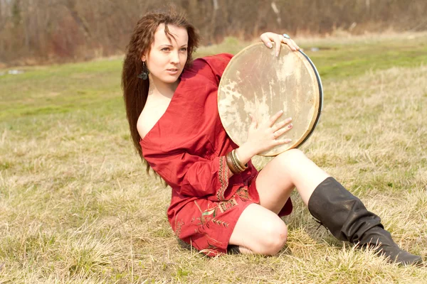Jeune fille assise sur le sol et tient un tambourin — Photo