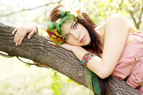 Jovem menina bonita deitada em um tronco de árvore — Fotografia de Stock