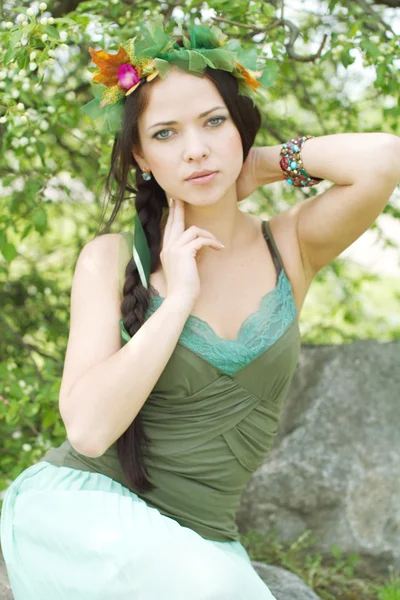Beautiful young woman sitting on stones — Stock Photo, Image