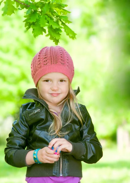 Adorable niña en sombrero rosa sonriendo en un parque —  Fotos de Stock
