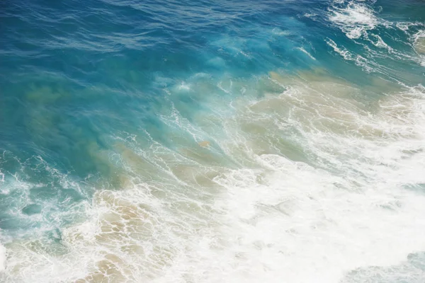 Blaues Wasser mit weißem Schaum am Meeresufer — Stockfoto