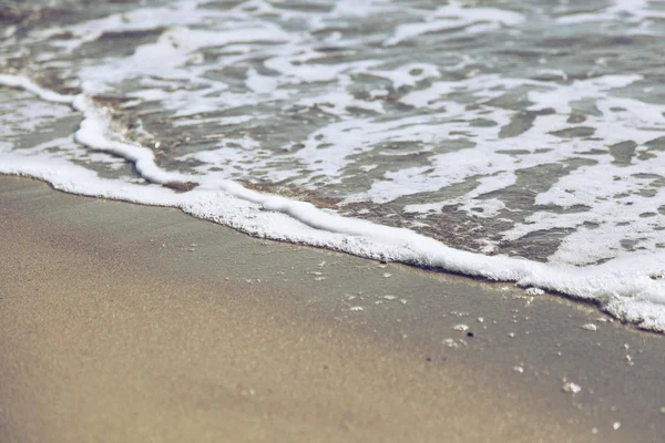 Skummande våg rullande på en sandstrand — Stockfoto