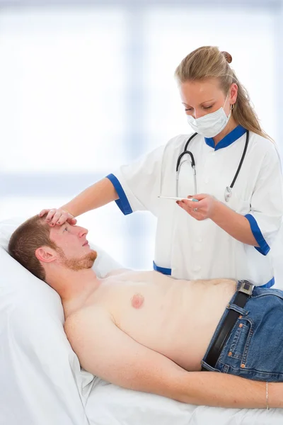 stock image Young doctor checking patients temperature - fever