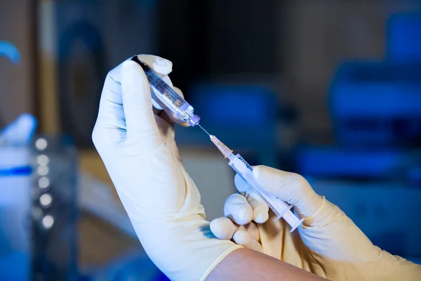 Ученый со шприцем, сосущей вакцину, двумя руками — стоковое фото