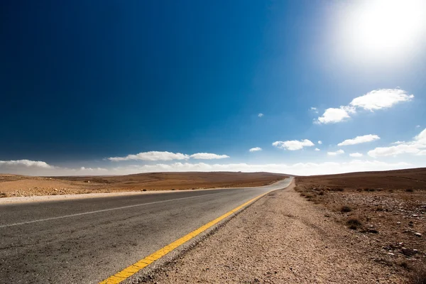 Leere Wüstenstraße mit blauem Himmel. — Stockfoto