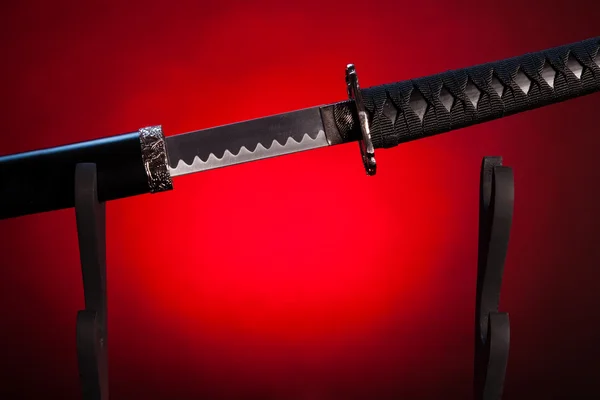 Katana on stand with red lighting, partially drawn blade. — Stock Photo, Image