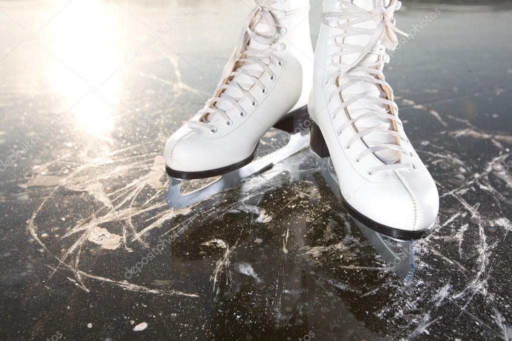 Wide skates on ice with sun reflected in behind