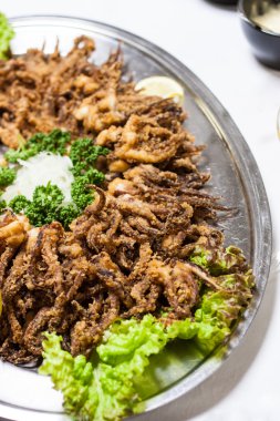 Fried octopuses and green lettuce on dinner table clipart