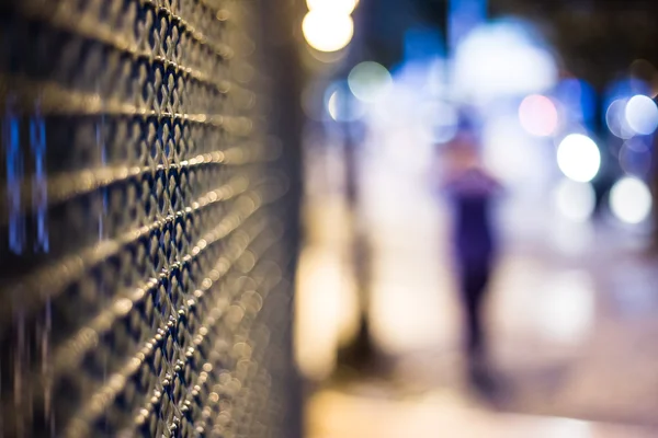 Mysterious night city, blurred figure and fence — Stock Photo, Image