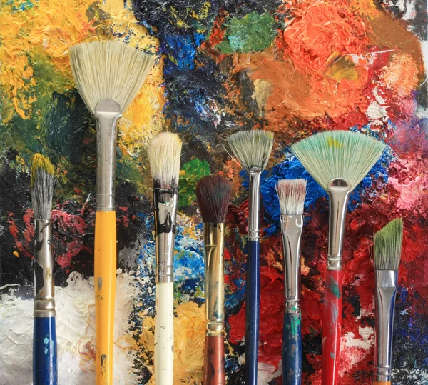 Pincéis de artista em um fundo de pintura a óleo — Fotografia de Stock