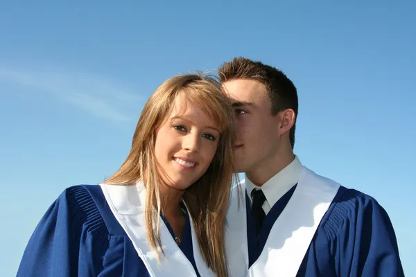Cute couple in graduation gowns — Stock Photo, Image