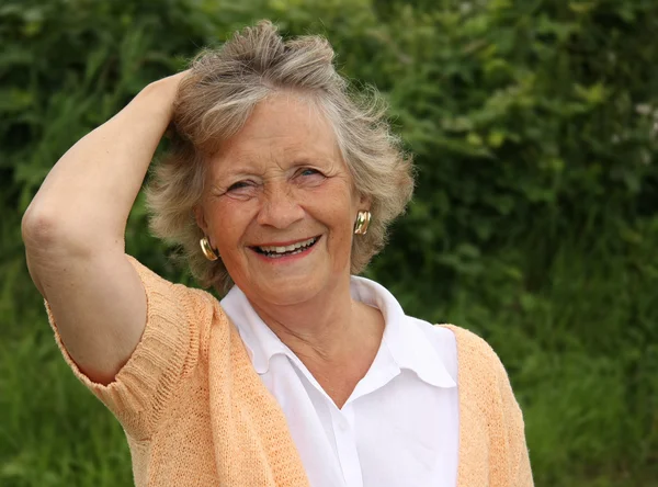 Dame in haar jaren zestig, glimlachend buiten in de tuin — Stockfoto