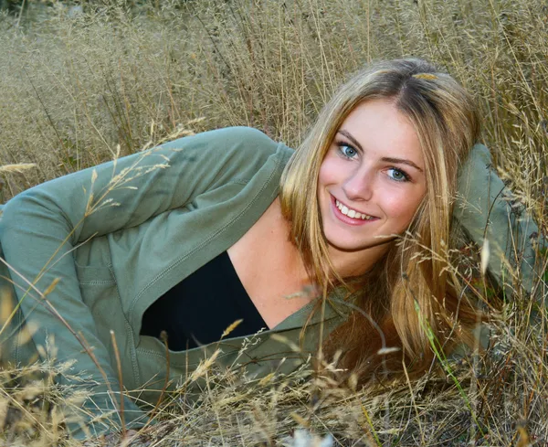 Menina adolescente bonita que coloca na grama alta — Fotografia de Stock