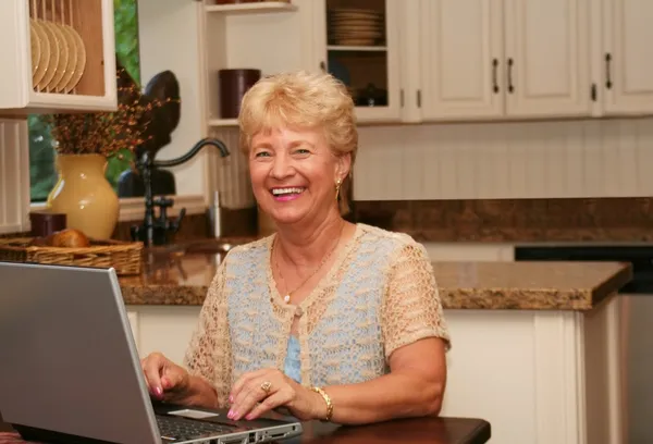 Grand-ma w kuchni przy użyciu swojego laptopa — Zdjęcie stockowe