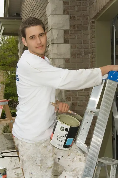 Joven, sosteniendo una lata de pintura y escalera — Foto de Stock