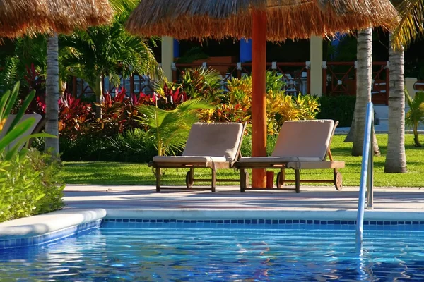 Zwembad kant lounge stoelen in een tropisch resort. — Stockfoto