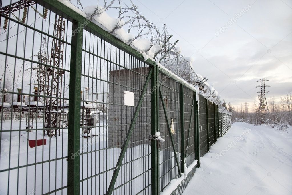 Electrical substation behind a fence topped with barbed wire