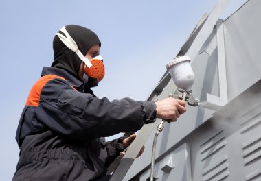 A commercial painter on the stairs spray painting a steel exteri clipart