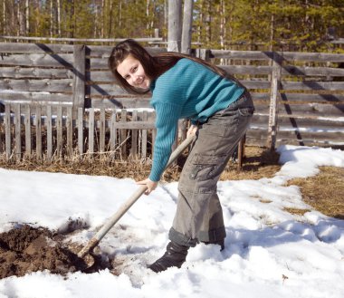 A young girl digs the garden in early spring clipart