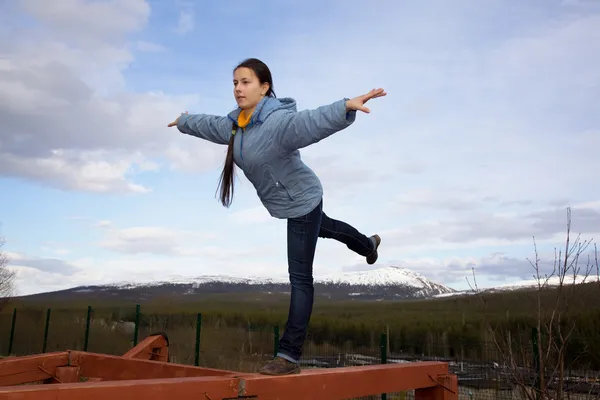 Flickan gör gymnastiska inslag av balansen på en stock — Stockfoto