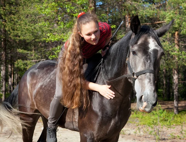 Uma menina com seu cabelo acariciando cavalo — Fotografia de Stock