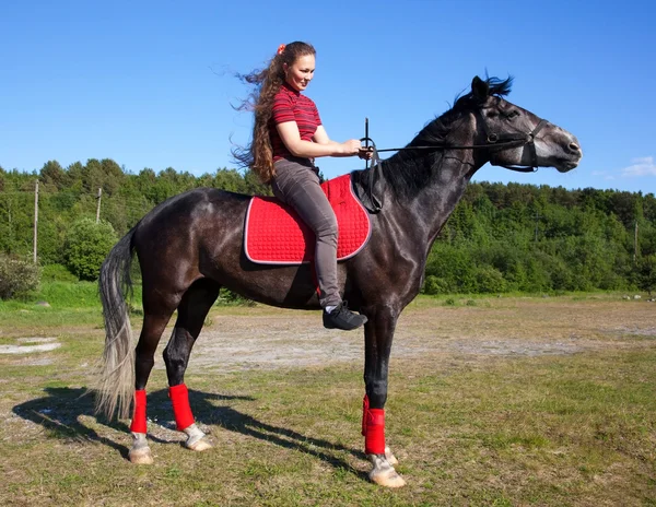 Flicka på en häst med håret fladdrande i vinden — Stockfoto