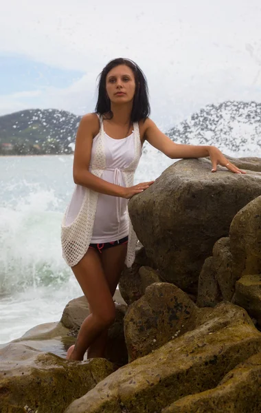 Okouzlující brunetka mezi kameny u moře — Stock fotografie