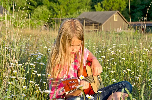 Dívka v poli s kytarou — Stock fotografie