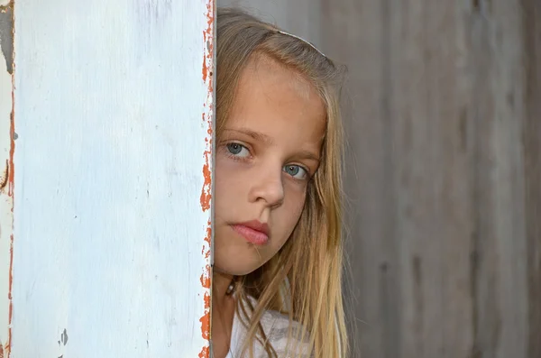 古いドアの周りのピークの女の子 — ストック写真