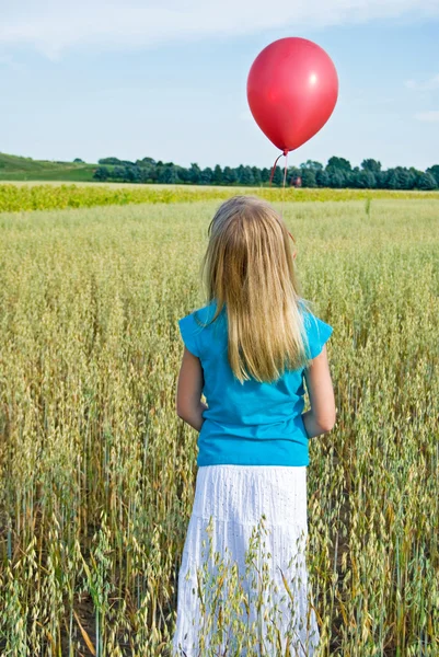 Girl releasing a red balloon — Stock Photo, Image