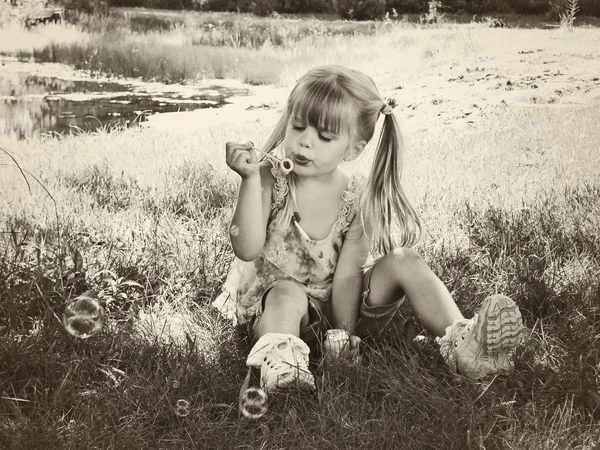 Маленька дівчинка дме бульбашки — стокове фото
