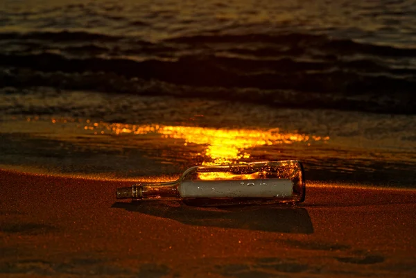 Butelka na plaży o zachodzie słońca — Zdjęcie stockowe