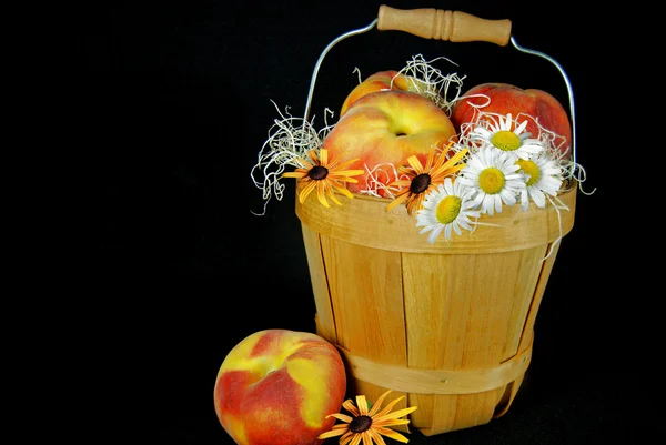 Perziken in de mand met madeliefjes — Stockfoto